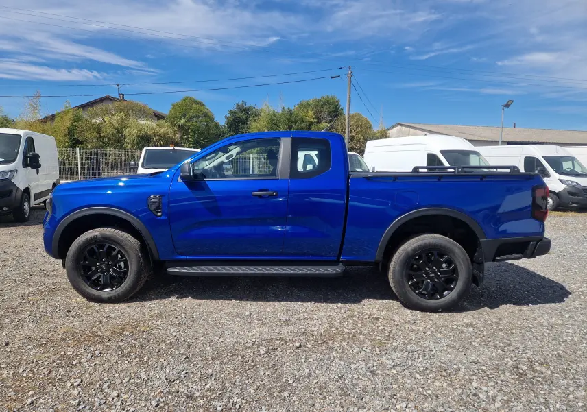 Ford Ranger Super Cabine bleu Lightning vu de profil côté gauche, avec marchepied et barres sur plateau.