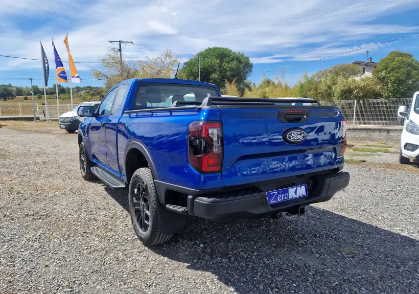 Vue 3/4 arrière droite d'un Ford Ranger Super Cabine bleu Lightning avec rideau de plateau rigide et barres sur plateau.