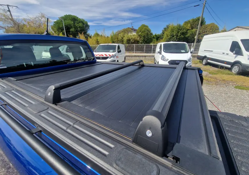 Vue arrière rapprochée du plateau avec rideau rigide coulissant et barres sur un Ford Ranger Super Cabine bleu Lightning.
