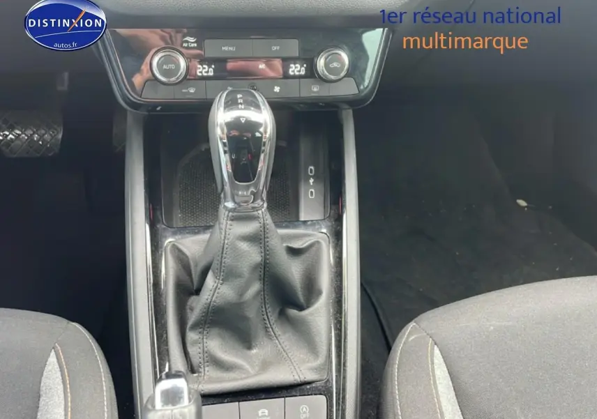 Vue rapprochée de la console centrale avec levier de vitesse automatique et sièges tissu gris du Skoda Kamiq 2025.