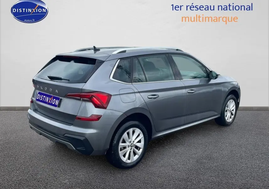 Vue 3/4 arrière droite d'un Skoda Kamiq gris 2025 avec barres de toit et jantes alu.