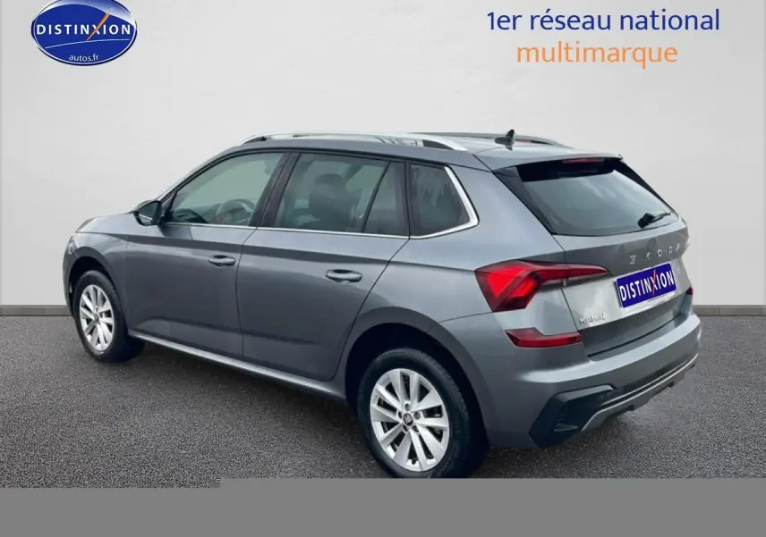 Vue 3/4 arrière droite d'un Skoda Kamiq gris 2025 avec barres de toit et jantes alu visibles.