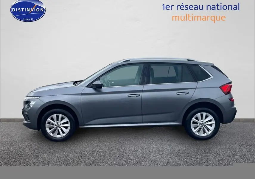 Profil droit d'un Skoda Kamiq gris 2025 avec jantes alu et barres de toit visibles sur fond neutre.