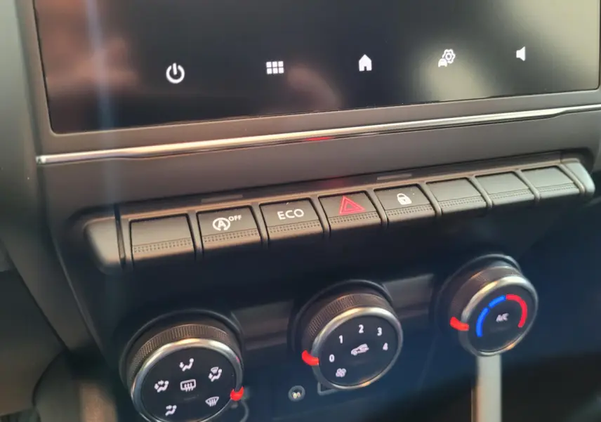Gros plan sur la console centrale de la Renault Clio gris foncé, montrant les boutons de commande et les réglages climatiques.