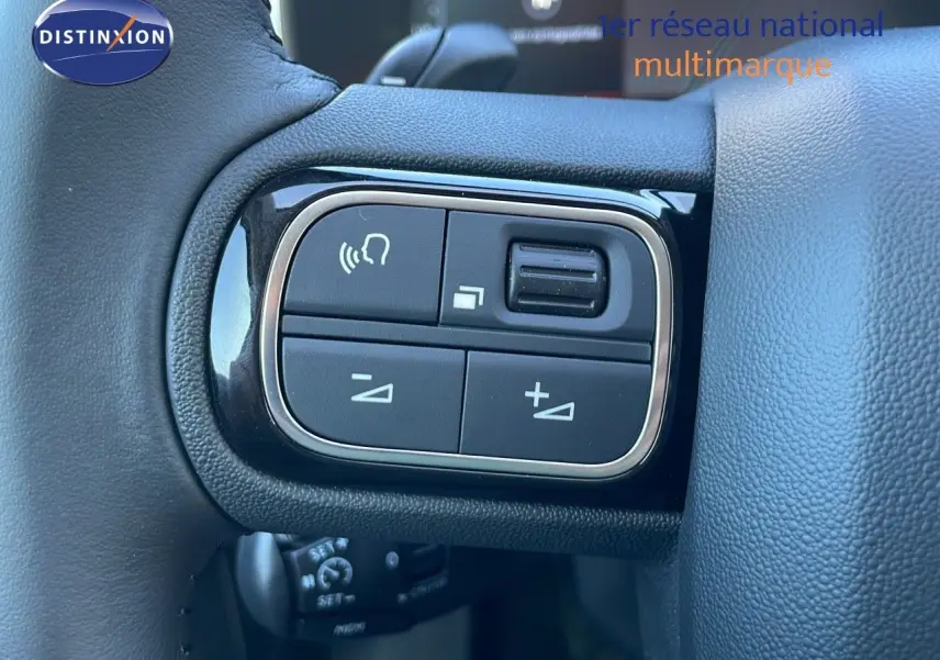 Gros plan sur les commandes du volant à gauche du Citroën C5 Aircross gris platinium 2025 avec toit noir.