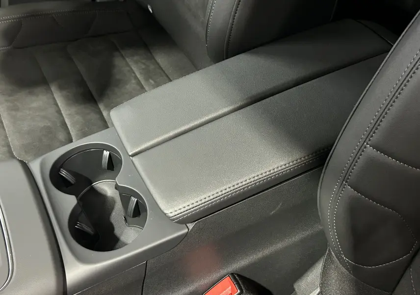 Gros plan sur l'accoudoir central et porte-gobelets noirs des sièges avant en cuir noir du Citroën C5 Aircross 2025.