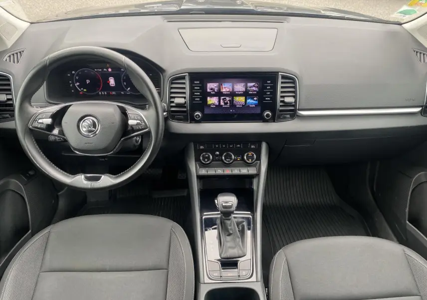 Vue intérieure frontale du tableau de bord et volant noir du Skoda Karoq gris graphite 2022 avec écran tactile central.
