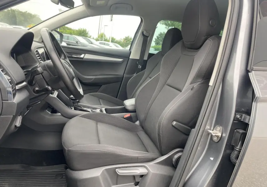 Intérieur côté conducteur du Skoda Karoq gris graphite, sièges tissu noir et tableau de bord visible en arrière-plan.