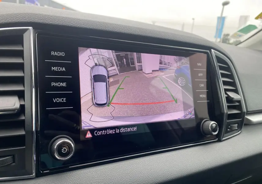 Écran tactile intérieur montrant la caméra de recul du Skoda Karoq gris graphite, avec lignes de guidage colorées.