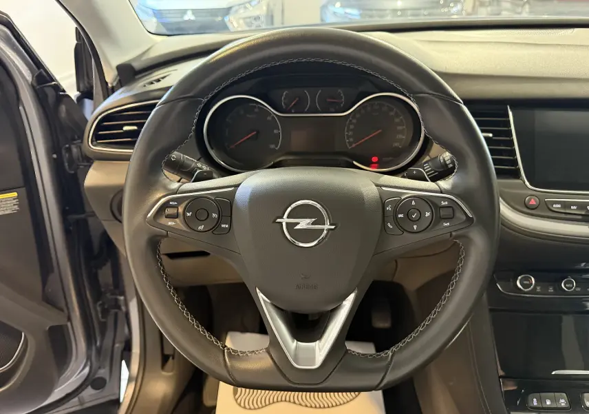 Vue rapprochée du volant en cuir noir de l'Opel Grandland X 2021, avec tableau de bord et écran tactile visibles.