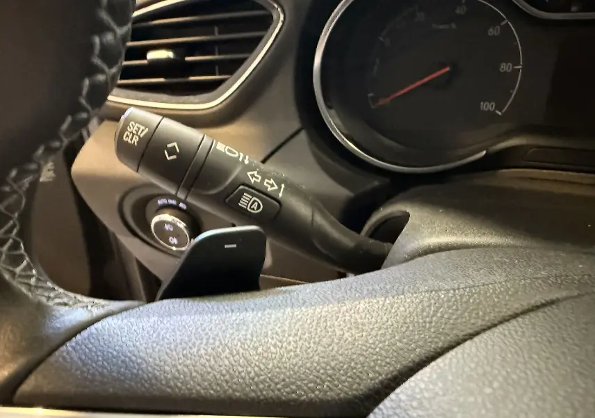 Gros plan sur le commodo gauche et le volant en cuir de l'Opel Grandland X hybride, tableau de bord partiellement visible.