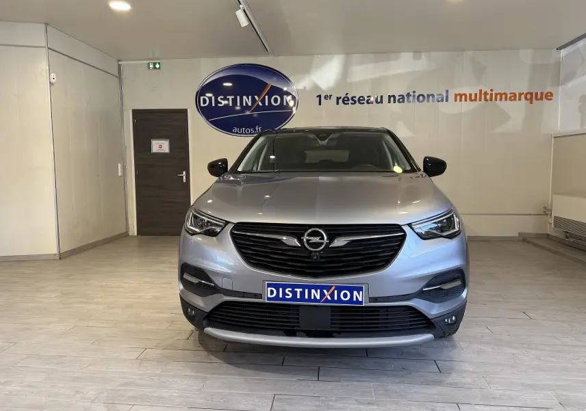 Vue frontale d'un Opel Grandland X gris Himalaya métallisé, avec calandre noire et logo Opel bien visible.