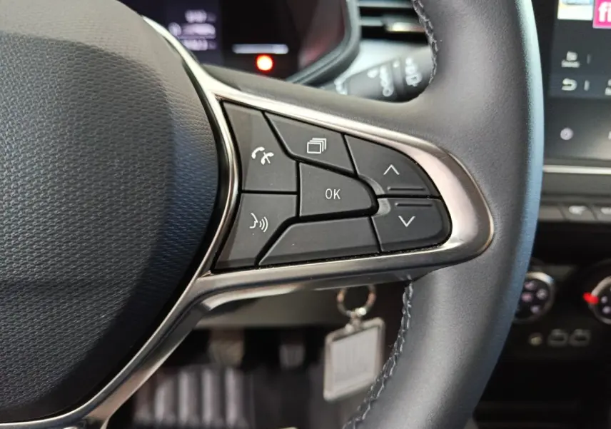 Gros plan sur les commandes multifonctions du volant cuir synthétique côté droit de la Renault Clio gris clair 2025.