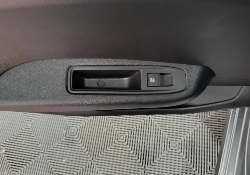 Détail de la poignée intérieure de porte côté conducteur de la Renault Clio gris clair, avec bouton de verrouillage.