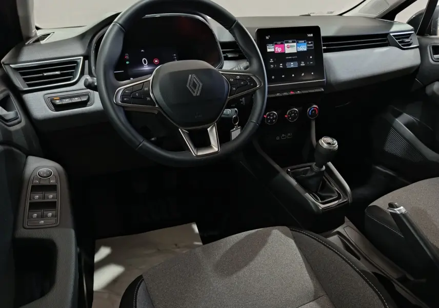 Vue intérieure côté conducteur de la Renault Clio gris clair 2025 avec volant cuir multifonctions et écran tactile central.