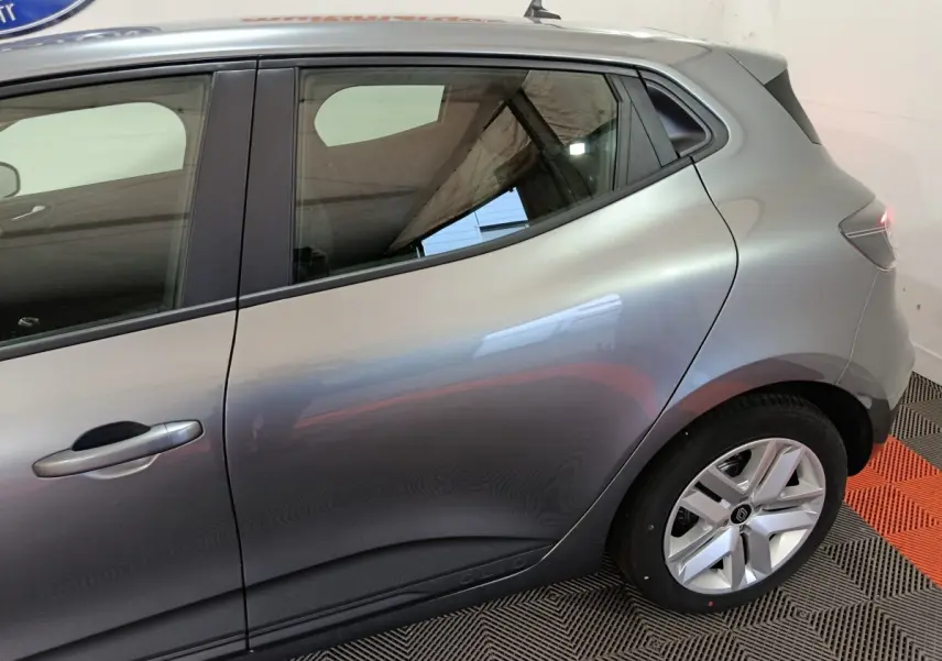 Vue latérale droite sur l'arrière d'une Renault Clio gris clair 2025, avec jante alliage et poignée de porte intégrée.