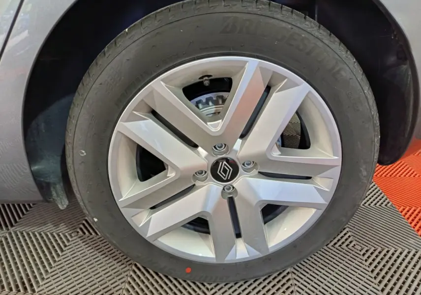 Gros plan sur la roue avant droite de la Renault Clio gris clair, mettant en valeur la jante alliage moderne et le pneu Bridgestone.