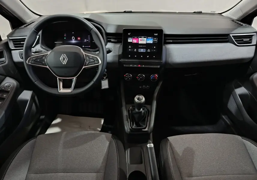 Vue frontale de l’habitacle de la Renault Clio gris clair 2025 avec volant multifonctions, écran tactile et boîte manuelle.