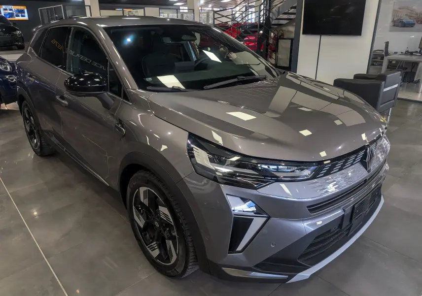 Vue 3/4 avant droite du Renault SYMBIOZ E-TECH Full Hybrid gris Cassiopé avec jantes bi-ton et calandre moderne en showroom.