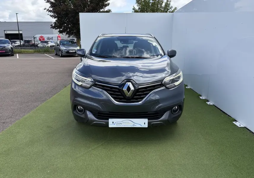 Vue frontale d'un Renault Kadjar gris titanium avec calandre chromée et projecteurs LED sur fond extérieur.