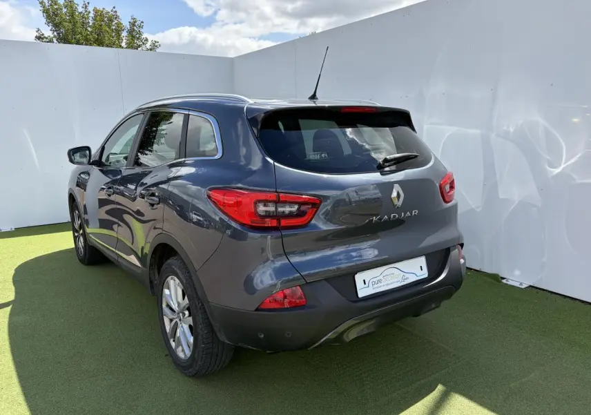 Vue 3/4 arrière droite d’un Renault Kadjar gris titanium avec jantes alliage et feux arrière LED, sur fond clair.