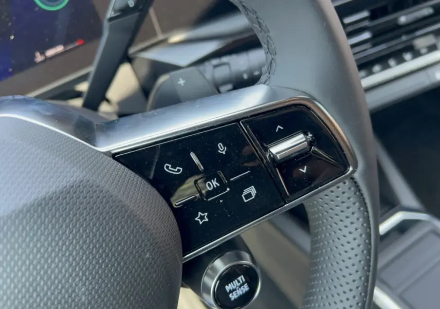 Gros plan sur les commandes multifonctions du volant de la Renault Clio gris rafale, version 2026.