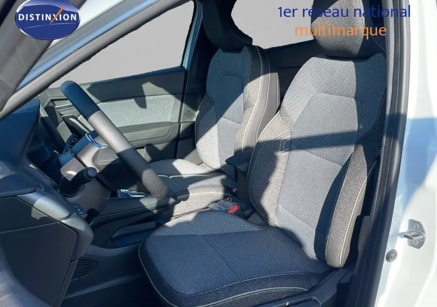 Vue intérieure côté conducteur du Renault Captur blanc nacré, sièges tissu gris clair et foncé avec surpiqûres blanches.