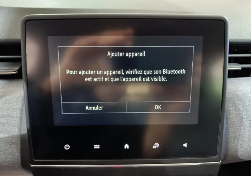 Écran tactile central affichant un message Bluetooth dans l'habitacle d'une Renault Clio gris clair, vue de face.