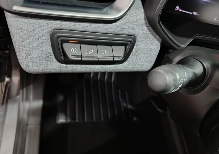 Vue rapprochée du tableau de bord côté gauche de la Renault Clio gris clair, avec commandes d’éclairage et verrouillage.