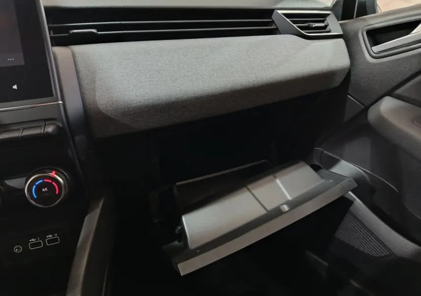 Vue intérieure côté passager de la Renault Clio 2025 avec boîte à gants ouverte et tableau de bord gris clair.