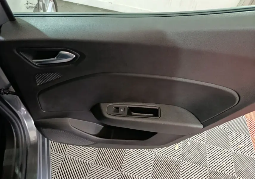 Vue intérieure de la porte côté gauche d'une Renault Clio gris clair, avec poignée argentée et commande de vitre.