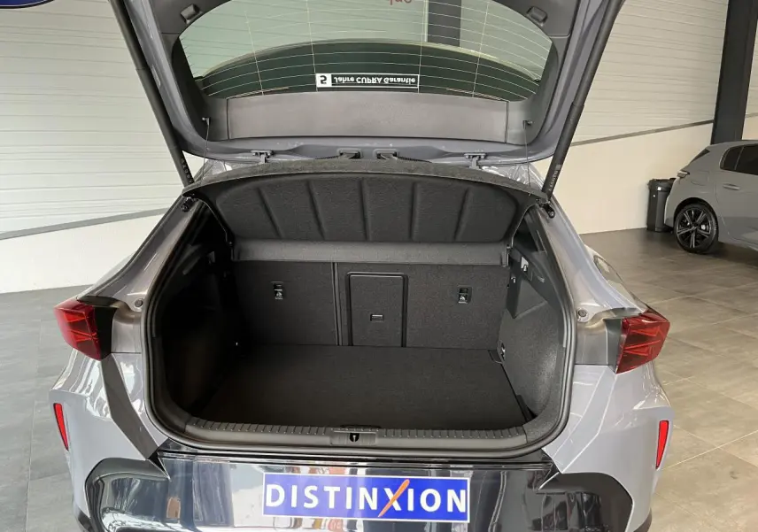 Coffre ouvert d’un CUPRA Formentor gris clair, vue arrière montrant l’espace de chargement et la signature lumineuse arrière.