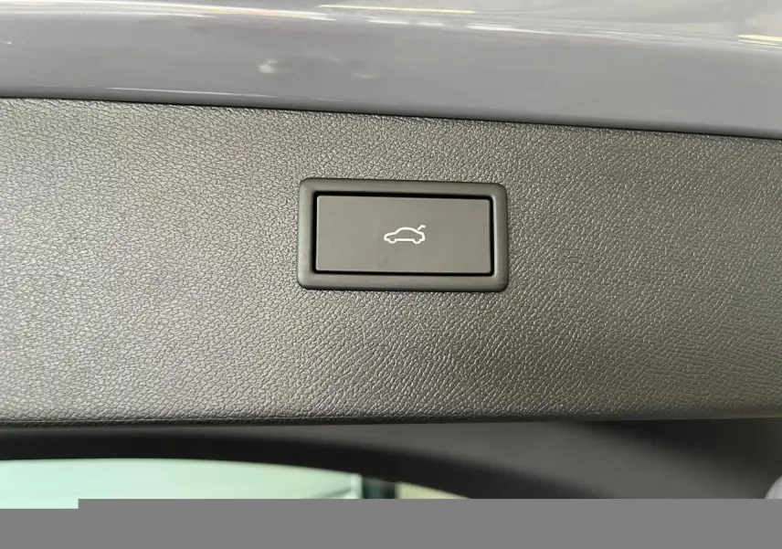 Bouton d'ouverture électrique du hayon sur la garniture intérieure noire du coffre du CUPRA Formentor gris clair.