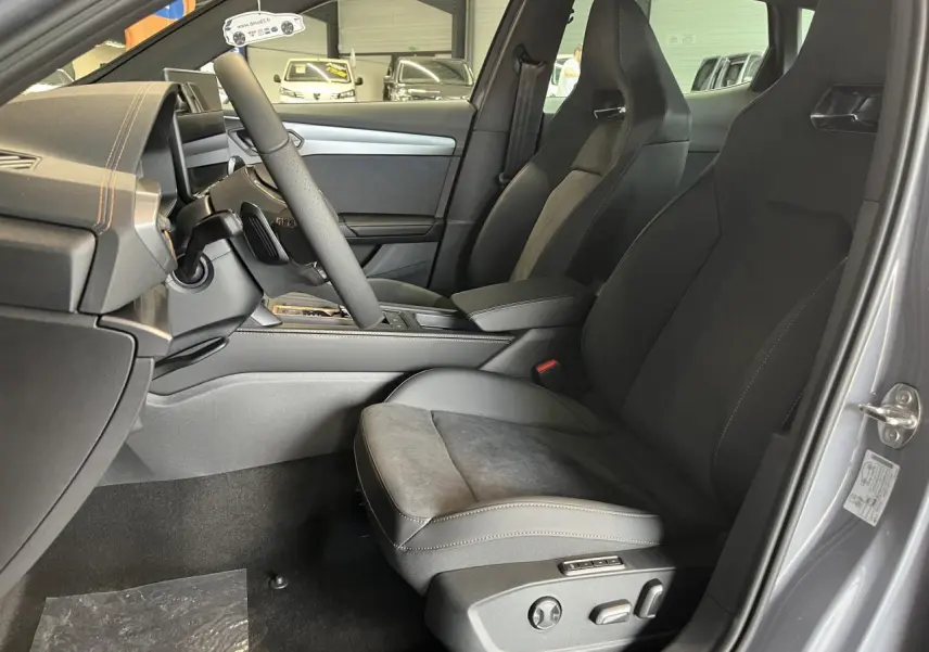 Vue intérieure côté conducteur du CUPRA Formentor 2025 gris clair, avec sièges sport et accoudoir central réglable.