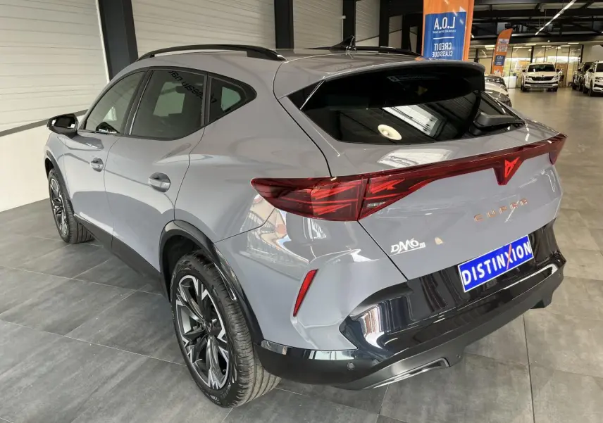 Vue 3/4 arrière droite du CUPRA Formentor gris clair avec bandeau lumineux arrière et jantes alliage 18 pouces.