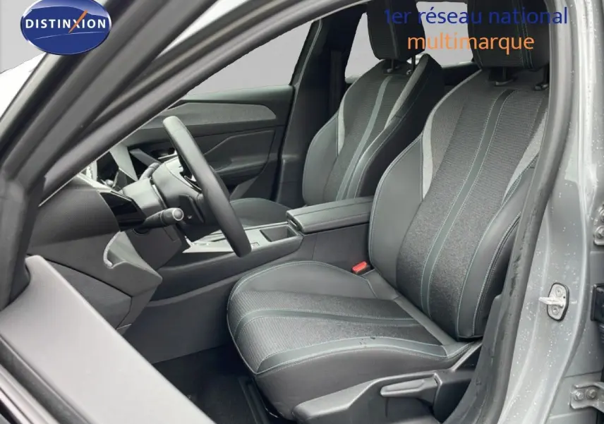 Vue intérieure côté conducteur de la Peugeot 408 2025 gris selenium, sièges tissu et cuir avec coutures contrastées.