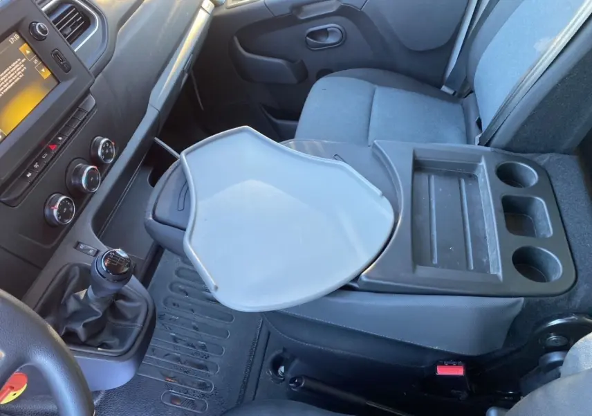Vue intérieure côté passager du Renault Master 2023, montrant la console centrale avec tablette rabattable et sièges gris.