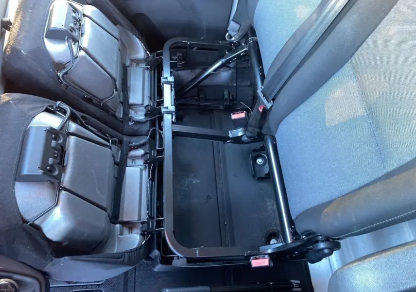 Vue intérieure rapprochée des sièges arrière rabattus du Renault Master 2023, montrant la structure métallique et les ceintures grises.