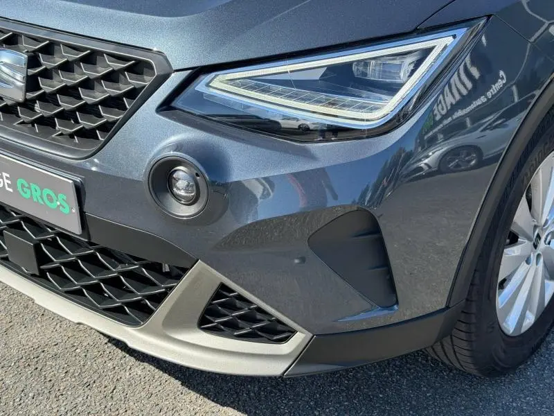 Gros plan sur l'avant droit gris magnétique métal du SEAT Arona 2025 avec phares LED et calandre noire ajourée.