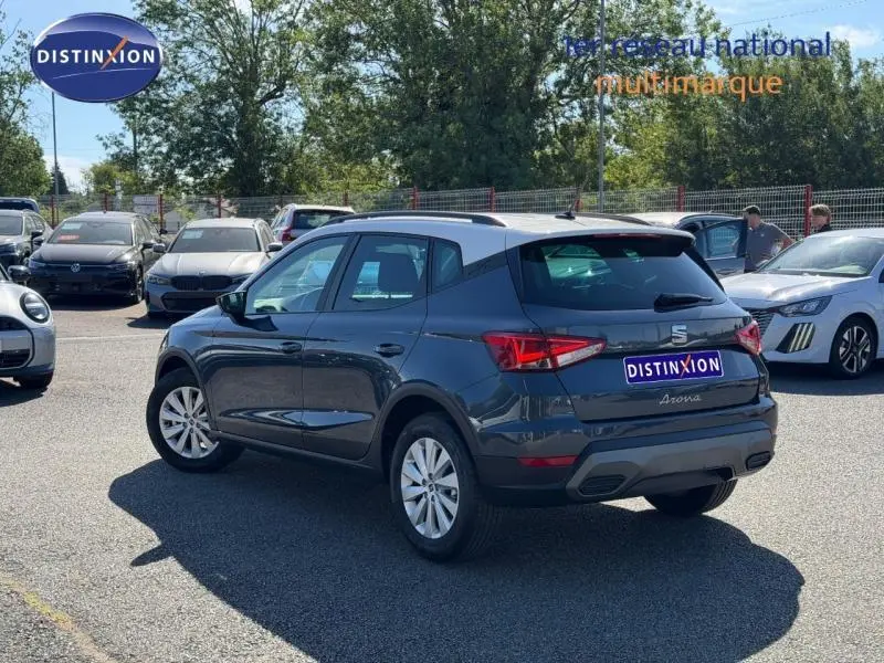 Vue 3/4 arrière droite d'une SEAT Arona gris Magnétique Métal avec toit blanc Candy, stationnée en extérieur.