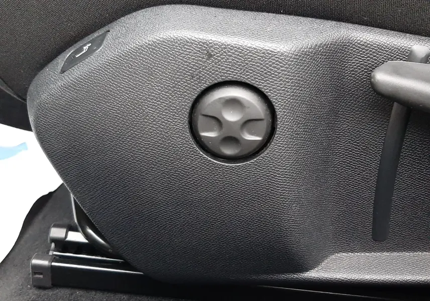 Détail du réglage manuel du siège en plastique noir à l'intérieur d'une Peugeot 508 blanche.