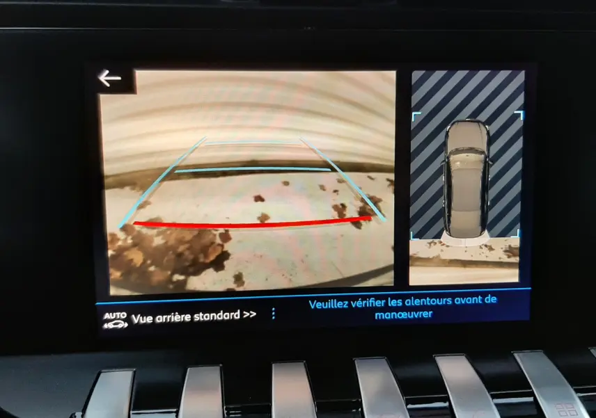 Vue de l'écran de caméra de recul de la Peugeot 508 blanche, affichant l'arrière et la vue 360° du véhicule en stationnement.