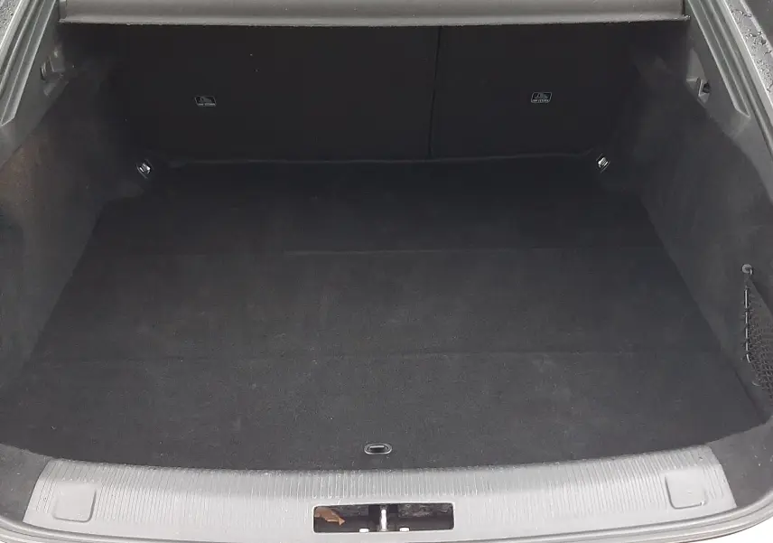 Coffre ouvert vu de l'arrière d'une Peugeot 508 blanche, espace de chargement vide avec cache-bagages noir.