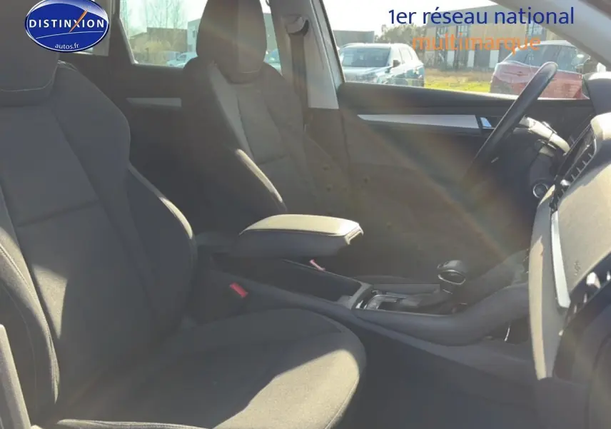 Vue intérieure côté droit du Skoda Karoq gris 2025, montrant les sièges avant et la console centrale avec accoudoir.