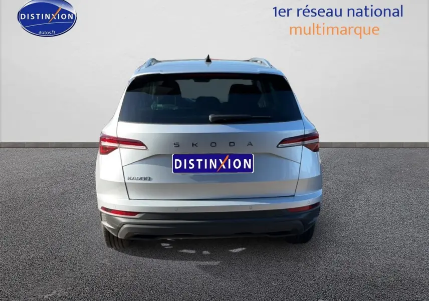 Vue arrière d'un Skoda Karoq gris 2025 avec feux arrière LED et barres de toit visibles.