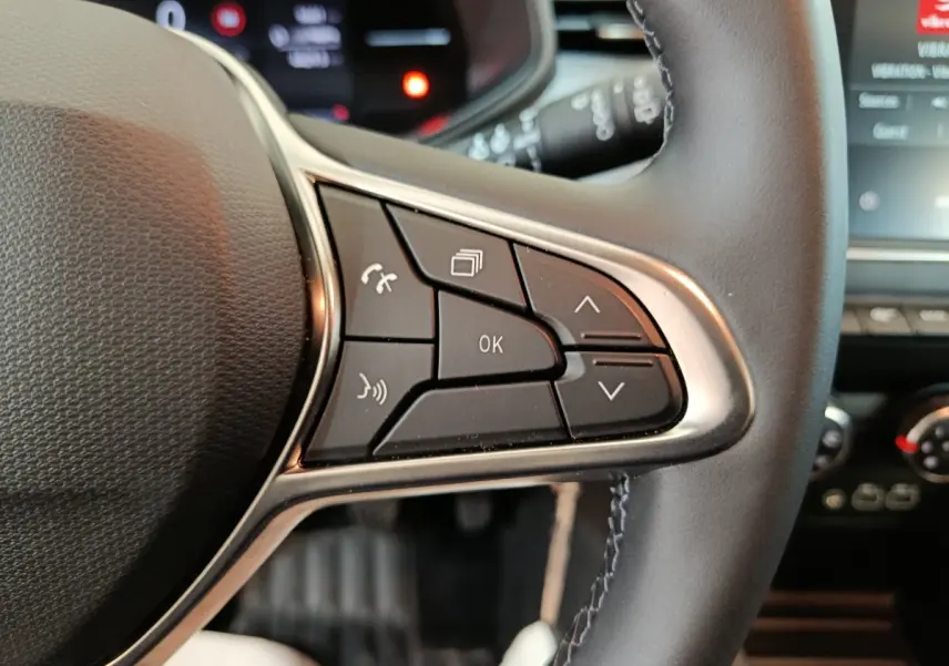 Gros plan sur les commandes multifonctions à droite du volant cuir noir de la Renault Clio Evolution Blue dCi 100 2025.