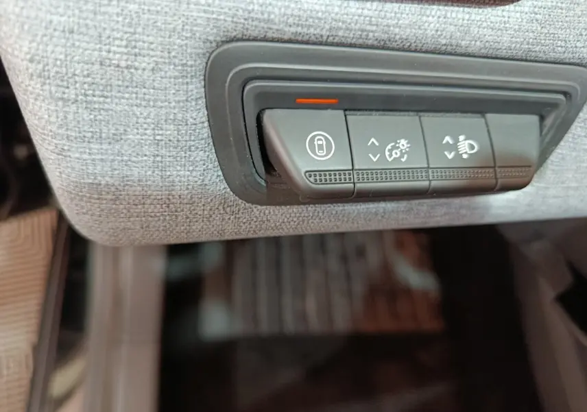 Gros plan sur les commandes de réglage des phares et verrouillage, intégrées dans le tableau de bord gris clair d’une Renault Clio noire.