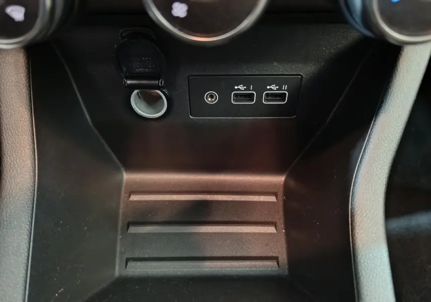 Gros plan sur la console centrale noire de la Renault Clio Evolution Blue dCi 100, avec prises USB et prise 12V visibles.