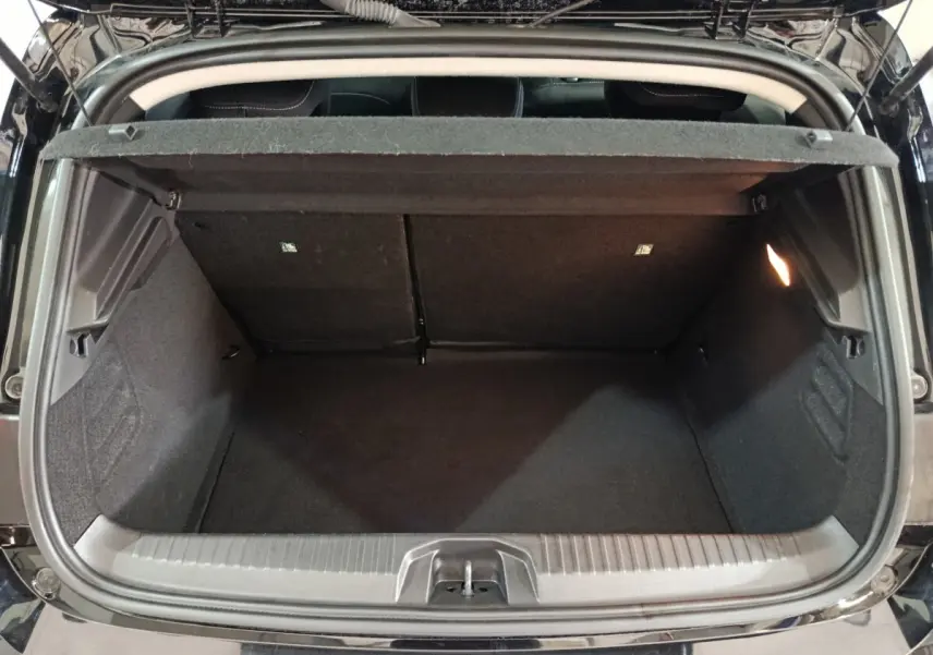 Vue arrière du coffre ouvert d’une Renault Clio noire, montrant l’espace de rangement intérieur et la tablette de séparation.