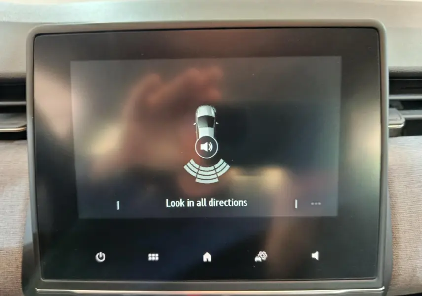 Écran tactile central affichant l'aide au stationnement d'une Renault Clio noire, vue intérieure du tableau de bord.